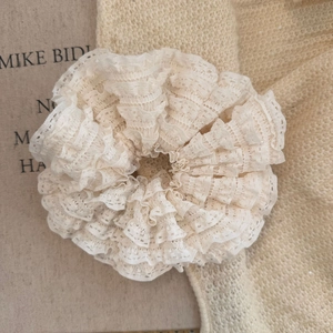 Macro view of French cream lace pleated hair scrunchie with layered fabric textures