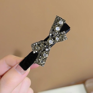 Elegant black velvet hair clip with champagne rhinestones and a delicate bow design
