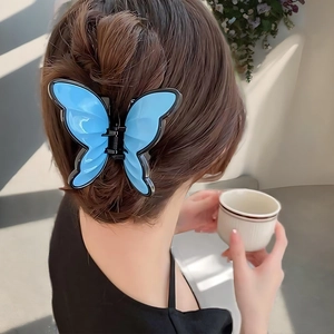 Detail view of a blue butterfly hair claw clip worn on a brown braided bun hairstyle