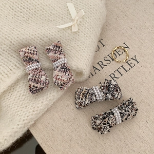 Detailed close-up of tweed bow hair clips featuring elegant pearl center accents