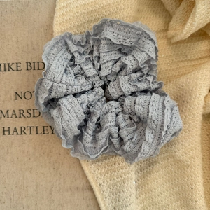 Close-up detail of light blue lace scrunchie with intricate embroidery and pleated texture