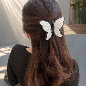 Detail of white butterfly hair claw clip with black outlines worn on long hair