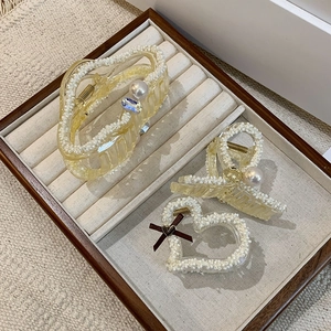 Elegant pearl resin hair claw clips set with ribbon bows and rhinestones on velvet tray