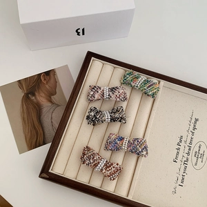 Detailed set of five tweed bow hair clips with pearls on a wooden display box