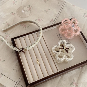 Detail of vintage pearl floral hair claw clips and headband on wooden jewelry tray
