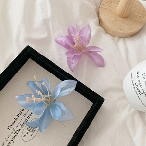 Détail de pinces à cheveux magnolia en soie bleu clair et violet sur un fond de tissu blanc