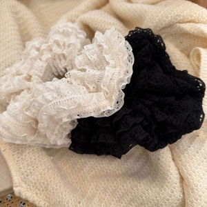 Detail of French lace scrunchies in white and black with layered ruffled texture