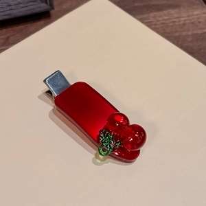 Detailansicht der roten Kirsch-Haarklammer mit glänzender Acryl-Oberfläche und Metallclip