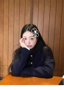 Close-up of a white woven floral hair clip with a pearl center worn by a model