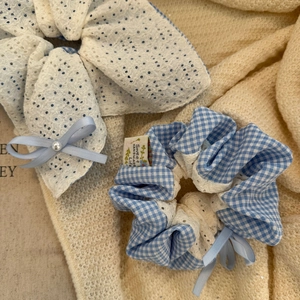 Détail d'un nœud en dentelle blanche avec ruban bleu et chouchou à carreaux bleu