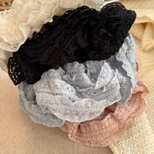 Macro shot of layered lace scrunchies in cream, black, and pastel blue colors