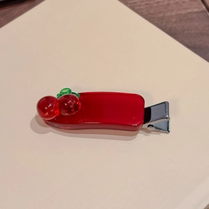Nahaufnahme einer Haarspange mit roter Kirsche aus Harz und silberner Metallbasis