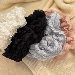 Close-up of elegant lace scrunchies in white, black, blue, and pink on a soft blanket