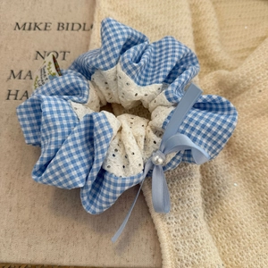 Détail d'un chouchou à carreaux bleus avec dentelle blanche, nœud et perle