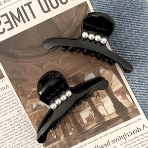 Dettaglio di due fermagli per capelli neri con perle su sfondo vintage con 4 perle per clip