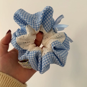 Détail d'un chouchou à carreaux bleus avec bordure en dentelle et étiquette faite main