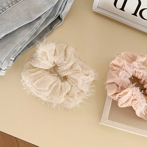 Dettaglio di elastici scrunchie arricciati color crema e rosa con piume decorative