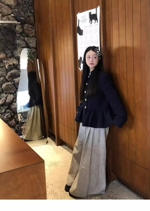 Detail of a navy short jacket with gold buttons and pleated wide-leg khaki trousers
