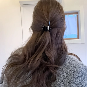 Dettaglio di un mollettone nero con perle eleganti indossato su capelli lunghi