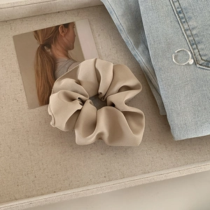 Detail view of a beige ribbed fabric scrunchie with rich texture and elastic structure