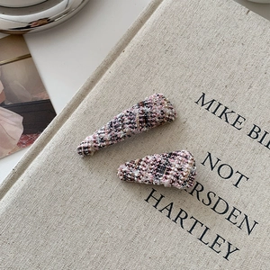 Close-up of pink and black tweed fabric texture on two small elegant hairpin accessories
