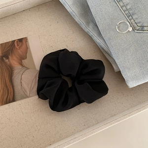 Close-up of black scrunchie with ribbed fabric texture on a modern lifestyle background
