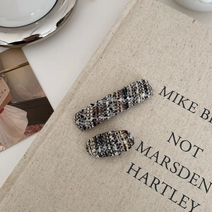 Detail of tweed fabric hair clips with a mix of black, white and brown woven textures