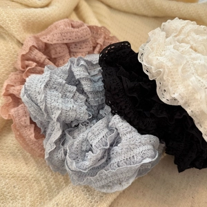 Set of four lace pleated hair scrunchies in pastel colors on a soft cream knit background