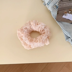 Elastico scrunchie rosa arricciato con bordo a frange bianche su sfondo estetico