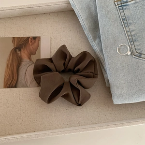 Detailed view of large dark brown satin scrunchie with soft ribbed texture for hair styling