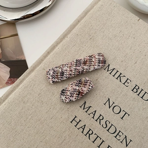 Detail of tweed fabric hair clips set in pink and black plaid pattern on canvas