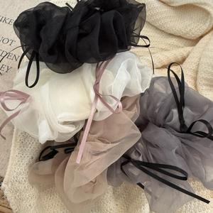 Détail de chouchous en tulle en quatre couleurs avec nœuds sur fond en maille douce