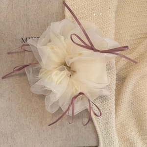 Vue macro détaillée d'un chouchou en organza crème avec des rubans de soie bordeaux