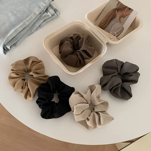 Set of five silky satin scrunchies in coffee tones on a minimalist white table