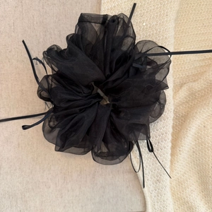 Détail du chouchou en maille noire avec longs rubans et pétales d'organza superposés