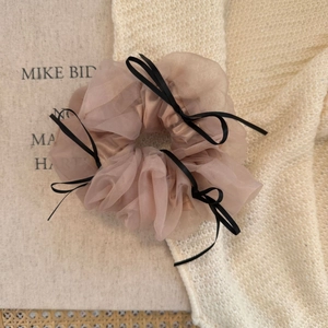 Détail d'un chouchou en organza rose orné de cinq délicats nœuds en ruban noir
