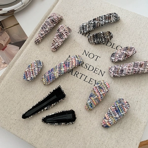 Close-up of assorted tweed fabric hair clips with metal duckbill clips on linen background