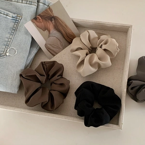 Satin silk hair scrunchies set in earth tones displayed on a minimalist linen tray