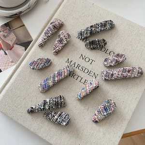 Close-up of 11-piece tweed fabric hair clips set with diverse shapes on a book prop