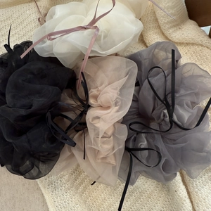 Détail de quatre chouchous en organza avec de délicats nœuds en ruban de tons neutres