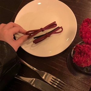 Élégantes barrettes à nœud rouge vin en faux daim posées sur une assiette décorative