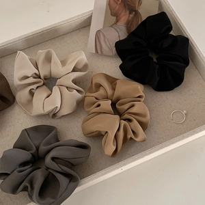 5-piece set of silk satin scrunchies in cream and brown tones on a minimalist linen tray