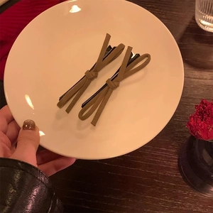 Gros plan de pinces à cheveux à nœud en daim vert olive avec base en métal noir