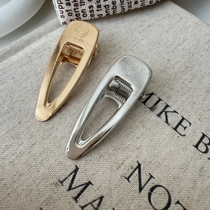 Detailed macro of gold and silver hair clips with smile engraving on canvas background