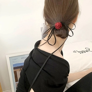Close-up of a burgundy rose hair tie with black ribbons styled on a low bun hairstyle