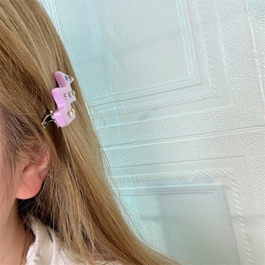 Detail einer lila Acetat-Haarklammer mit bunten Strasssteinen am Haar eines Models