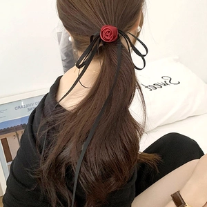 Detail view of the deep red velvet rose hair tie with elegant long black ribbons