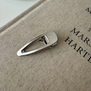 Macro detail of silver teardrop hair clip with Smile engraving and brushed metal finish