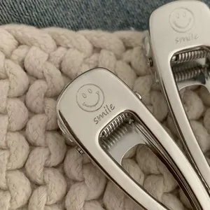 Detailed macro view of polished silver metal hair clip with smile engraving and text