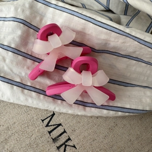 Détail de pinces à cheveux rose clair avec nœuds blancs mats sur tissu rayé